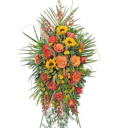 Tall standing floral spray with orange roses and yellow sunflowers on an easel