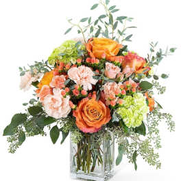 Orange and peach roses with hydrangeas in a clear glass vase