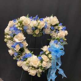 Heart-shaped floral wreath with cream roses, white blooms, and blue flowers