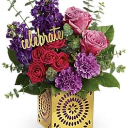 Bouquet of pink and purple flowers in a decorative yellow box with a "celebrate" sign