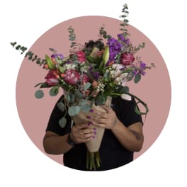 Large bouquet of pink, purple, and white flowers wrapped in paper