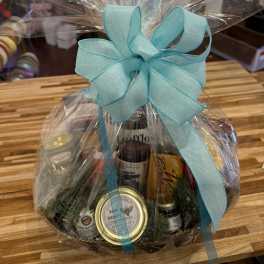 Gift basket wrapped in clear cellophane with a turquoise bow