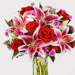 Bouquet of red roses and pink lilies in a clear glass vase