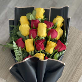 Bouquet of red and yellow roses wrapped in black paper with a red bow