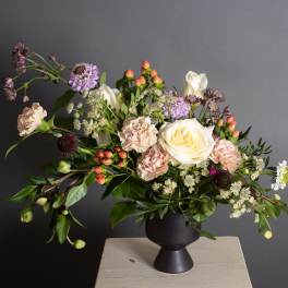 Mixed bouquet in a black vase with cream, pink, and purple blooms