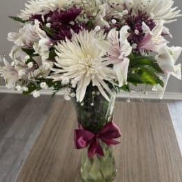 White and purple chrysanthemum bouquet in a glass vase with a ribbon