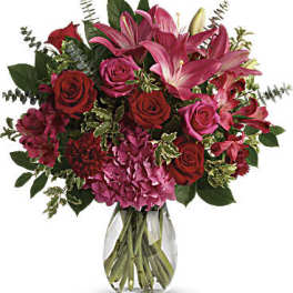 Bouquet of pink lilies and red roses in a clear glass vase