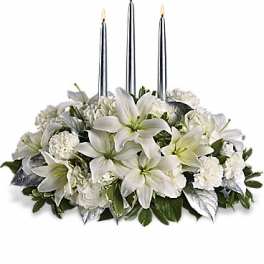 White floral centerpiece with three lit silver candles