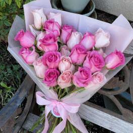 Bouquet of pink and pale pink roses wrapped in light paper with a ribbon