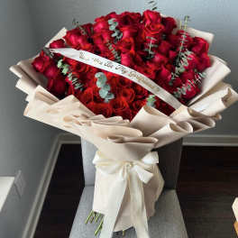 Large bouquet of red roses wrapped in cream paper with a ribbon
