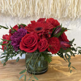 Red and purple flower arrangement in a glass vase