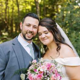 Bride and groom holding a pink rose bouquet outdoors