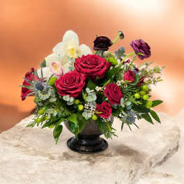 Red roses and white orchids in a black pedestal vase
