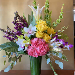 Mixed bouquet with hydrangea, orchids, roses, and lilies in a glass vase