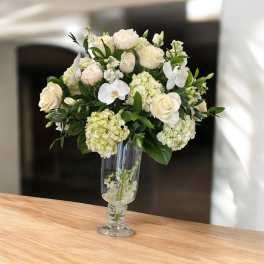 White roses and orchids arranged in a clear glass vase