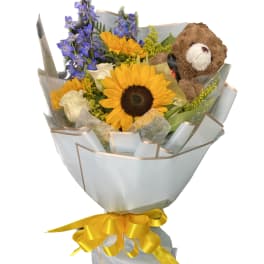 Bouquet of sunflowers, blue flowers, white roses, and a teddy bear