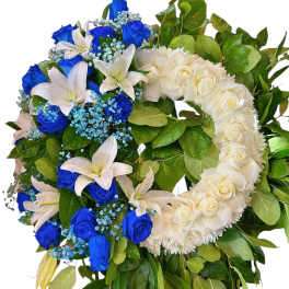 Heart-shaped wreath of blue and white roses with lilies and greenery