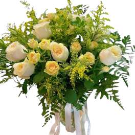Bouquet of cream roses with yellow filler flowers in a glass vase