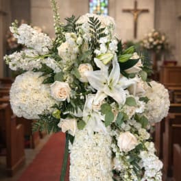 White floral funeral spray on an easel in a church