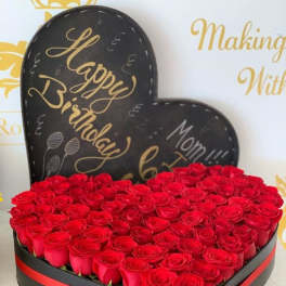 Heart-shaped box filled with red roses and a birthday sign