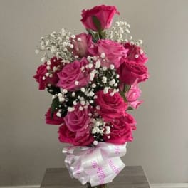 Pink rose bouquet in a glass vase with baby's breath and a ribbon bow