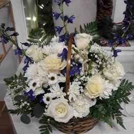 Basket arrangement of white roses and daisies with blue delphinium accents and ferns