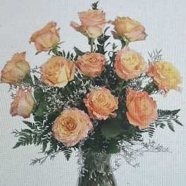 Arrangement of peach roses with white filler flowers in a clear glass vase