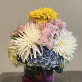Mixed bouquet in a glass vase with white, pink, yellow, and blue flowers
