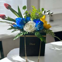 Bouquet of blue, white, and yellow flowers in a black Dior box