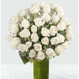 White roses arranged in a tall green glass vase
