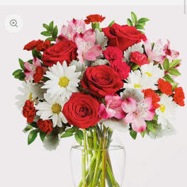 Bouquet of red roses, pink alstroemeria, and white daisies in a clear glass vase
