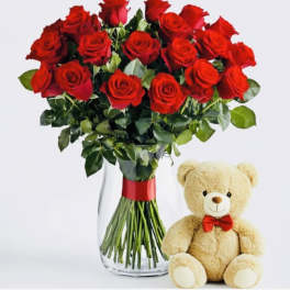 Bouquet of red roses in a glass vase with a teddy bear