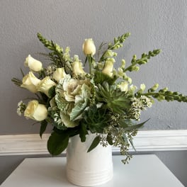 Cream roses and green succulents arranged in a white vase