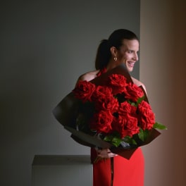 Woman holding a large bouquet of red roses wrapped in dark paper