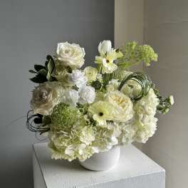 White floral arrangement in a white vase with roses and hydrangeas
