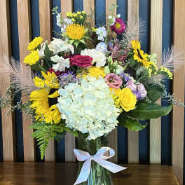 Mixed bouquet in a glass vase with a white ribbon