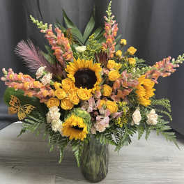 Large bouquet with sunflowers, yellow roses, and pink snapdragons in a glass vase