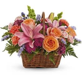 Basket arrangement with pink lilies, peach roses, and purple flowers