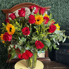 Bouquet of red roses and sunflowers in a clear glass vase