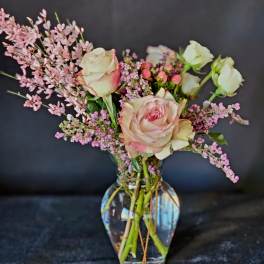 Pink and white roses in a clear glass vase with small pink filler flowers
