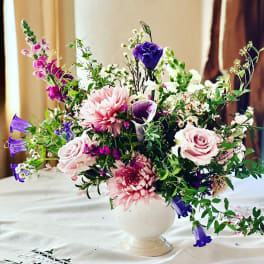 Mixed pink, purple, and white flowers arranged in a white vase
