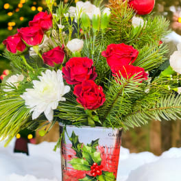 Red roses and white flowers in a holiday-themed vase