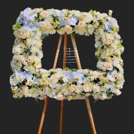 Square floral wreath on a wooden easel with white and blush flowers