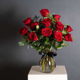 Bouquet of red roses in a clear glass vase with a black ribbon