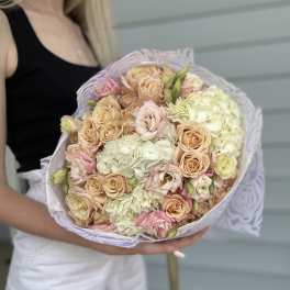 Handheld bouquet of blush roses and pale hydrangeas wrapped in lavender paper