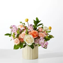 Mixed roses and pink blooms arranged in a striped gold vase