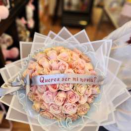 Bouquet of pale pink roses with a ribbon reading "Quieres ser mi novia?"