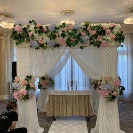 Wedding altar with pink and white floral arrangements and draped fabric