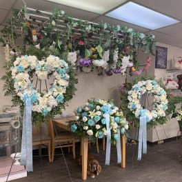 Heart-shaped floral wreaths on stands with blue and white flowers