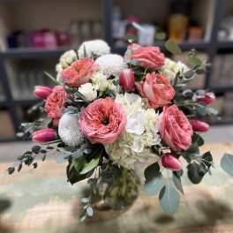 Bouquet of pink roses, white hydrangeas, and tulips in a glass vase